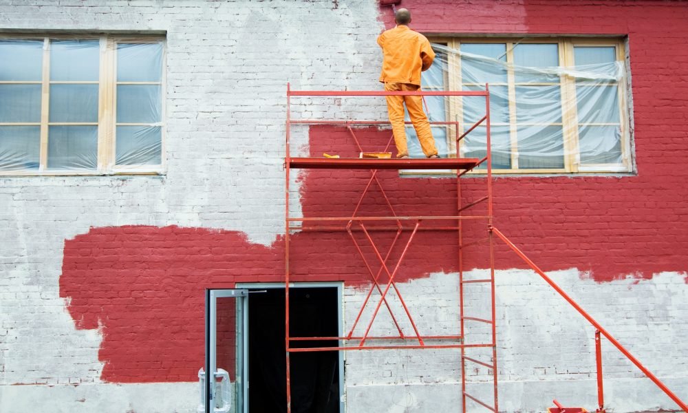 Man painting a brick wall in red